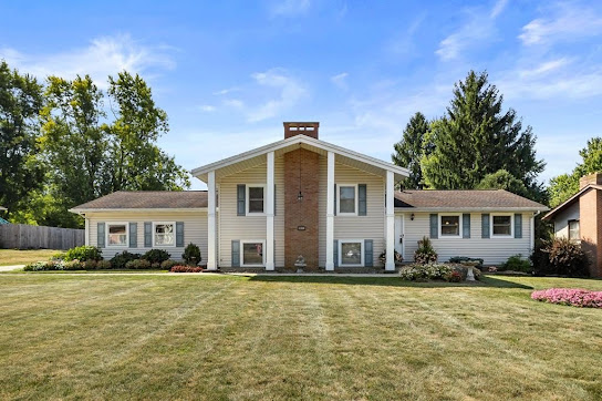 Cliffside Cottage — a split-level home with columned entry, brick chimney, and wide green lawn