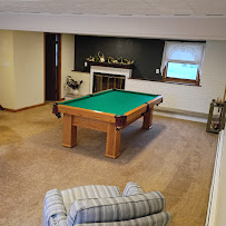 The lower-level game room with a green-felt pool table and comfortable couch